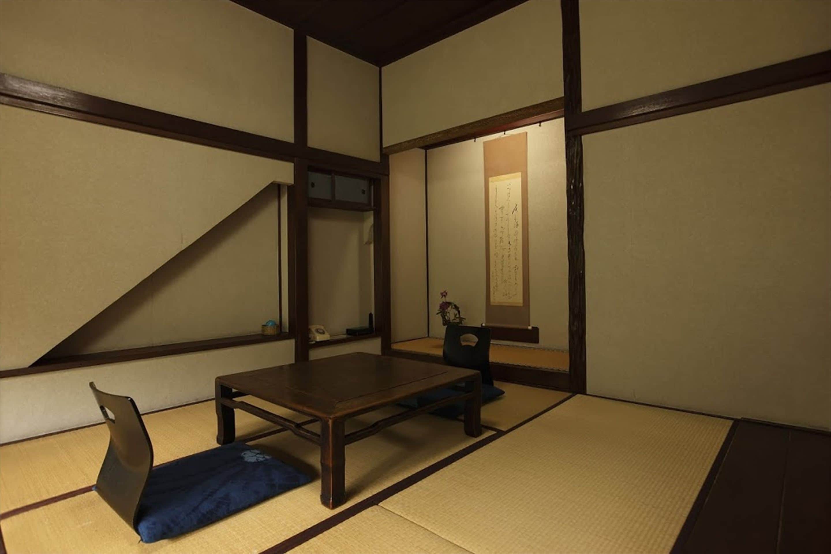 Una habitación japonesa tradicional con suelo de tatami, una mesa baja y una silla.