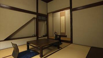 Una habitación japonesa tradicional con suelo de tatami, una mesa baja y una silla.