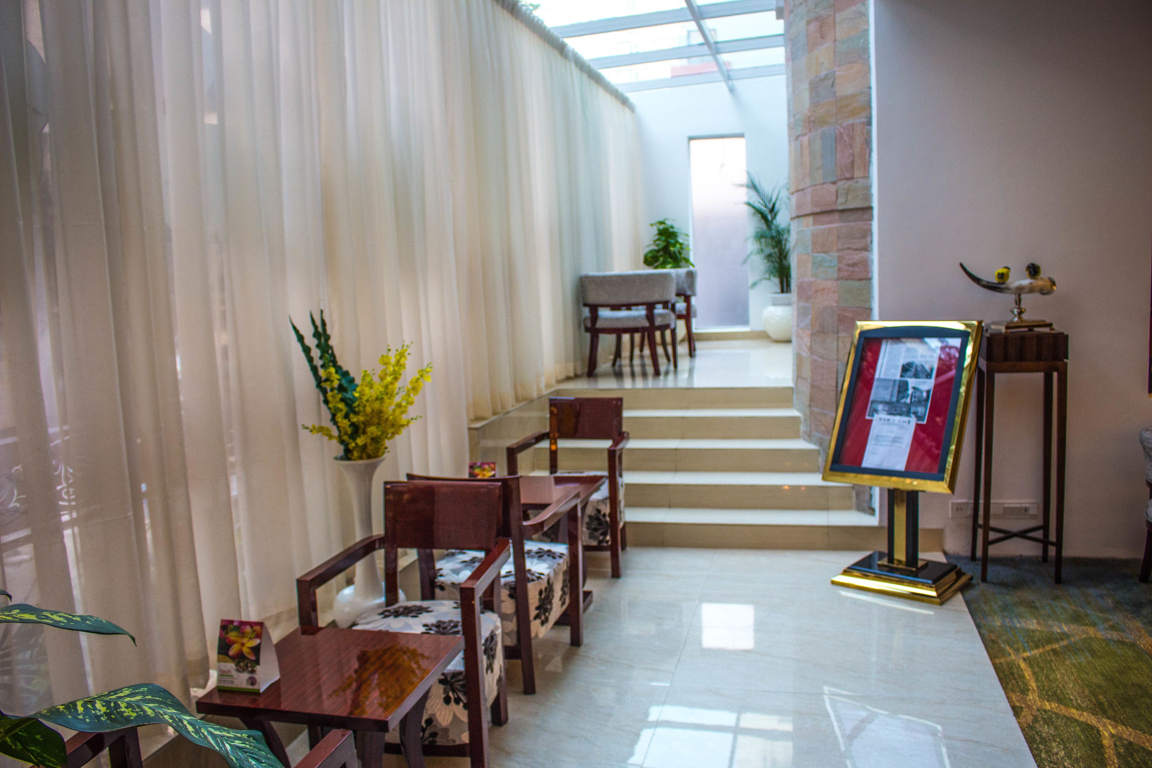 A hotel lobby with a staircase leading to a balcony, wooden furniture, and a framed display.