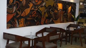 Un interior moderno con un cuadro abstracto grande en la pared, sillas de madera y una mesa de cristal.