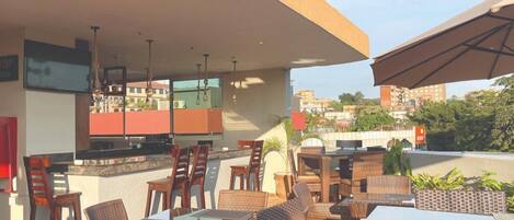 An outdoor dining area with wicker furniture, a bar, and a view of the cityscape.