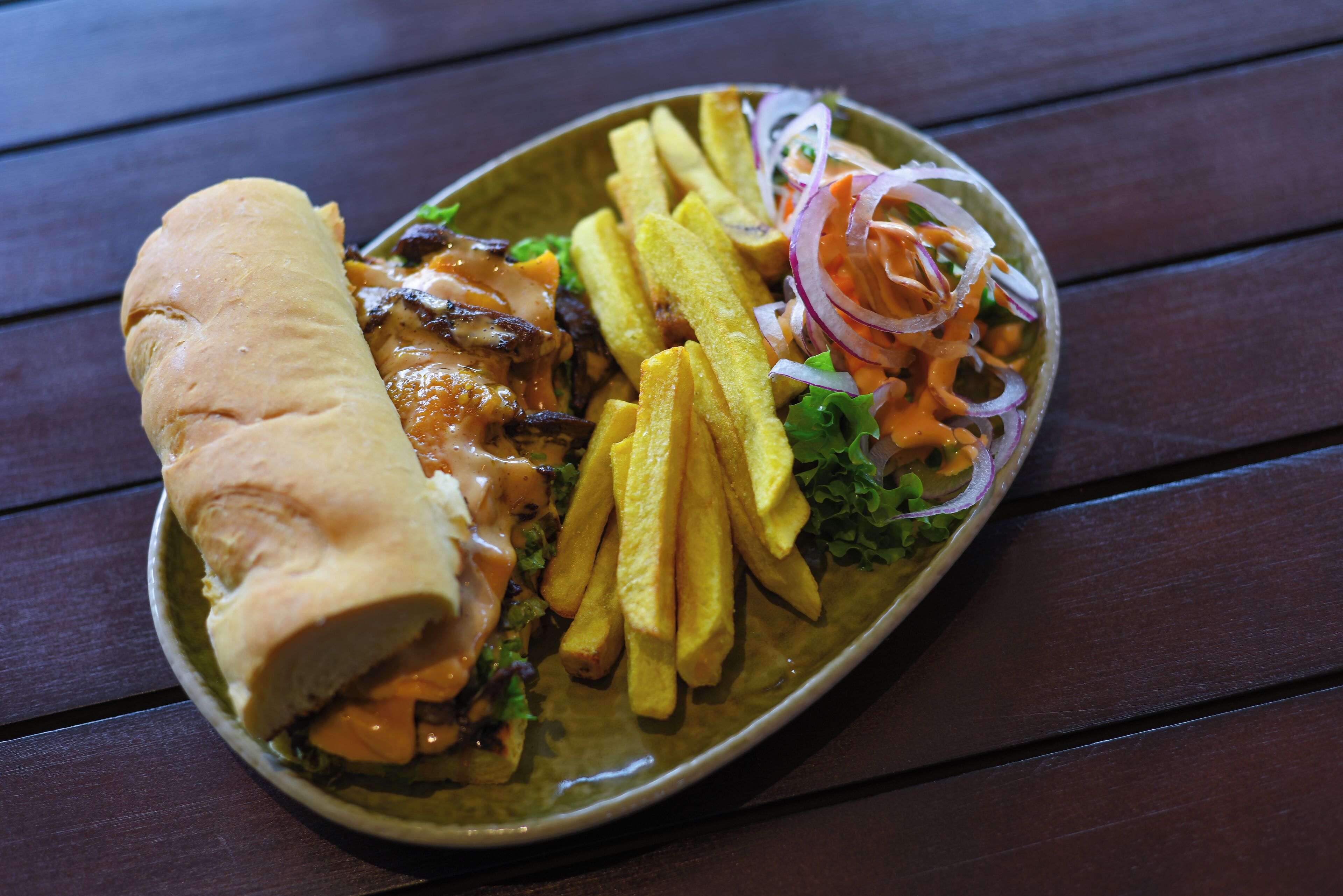Un sándwich acompañado de papas fritas y ensalada en un plato.