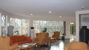 A spacious lobby with a curved sofa, armchairs, a coffee table, and a large vase. - Arcadia Suites (Kampala)