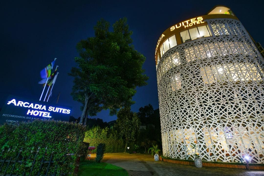 Exterior del Hotel Arcadia Suites, con una fachada de celosía distintiva y señalización iluminada.