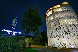 Exterior del Hotel Arcadia Suites, con una fachada de celosía distintiva y señalización iluminada.