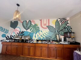 Una cocina con armarios de madera, una cafetera y un mural colorido en la pared.
