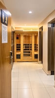 A hotel corridor with a sauna access notice, wooden lockers, and a tiled floor.