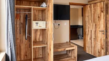Een hotelkamer met een bed, een houten kledingkast, een douchegedeelte en een aan de muur bevestigde televisie.