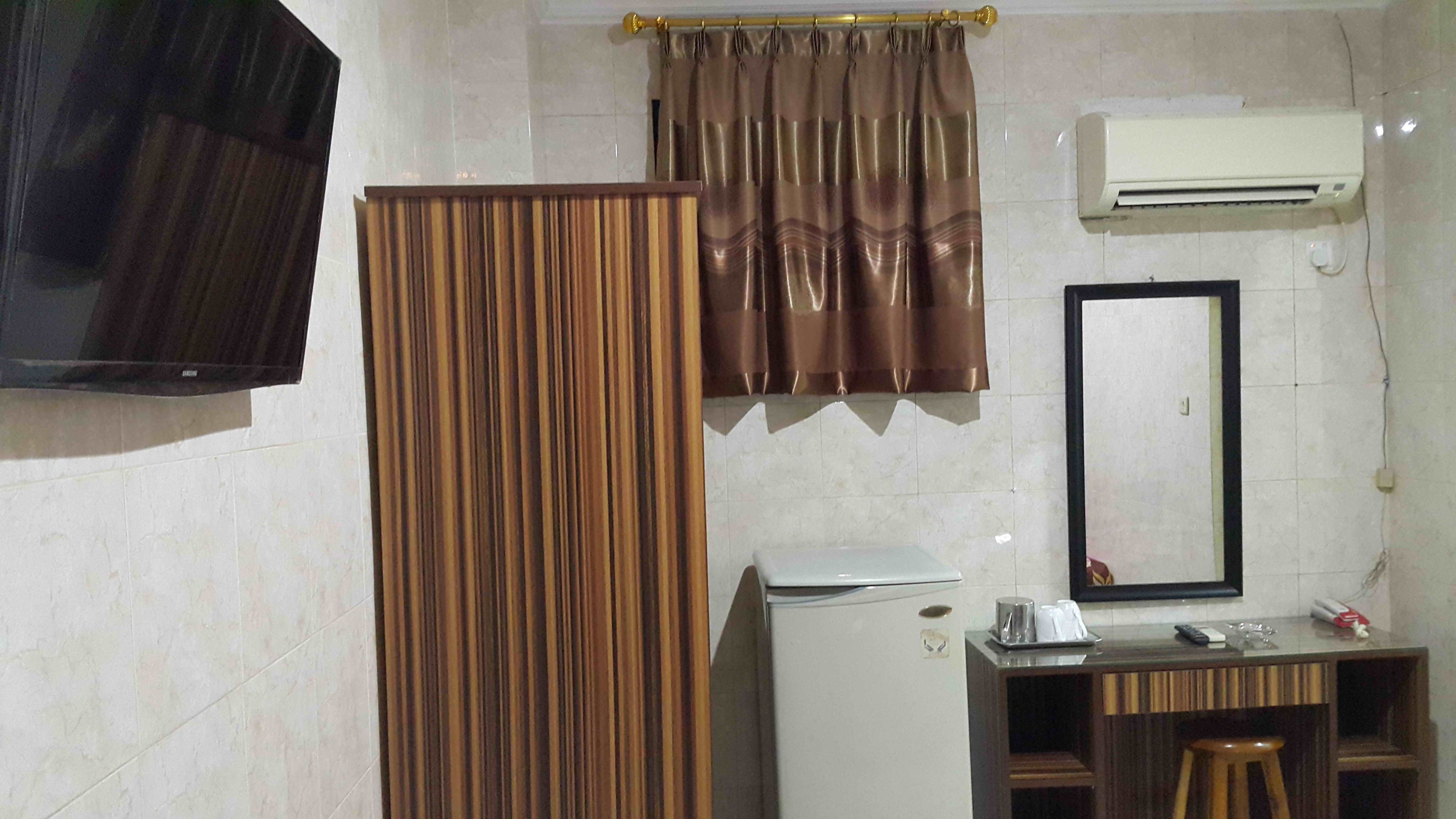 Un baño con cortina de ducha, espejo, aire acondicionado, lavabo e inodoro.