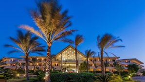 A large, multi-story hotel with a central atrium, surrounded by palm trees and well-lit pathways.