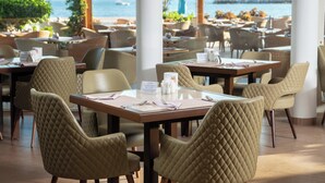 A restaurant with outdoor seating, tables with menus, and a view of the water.