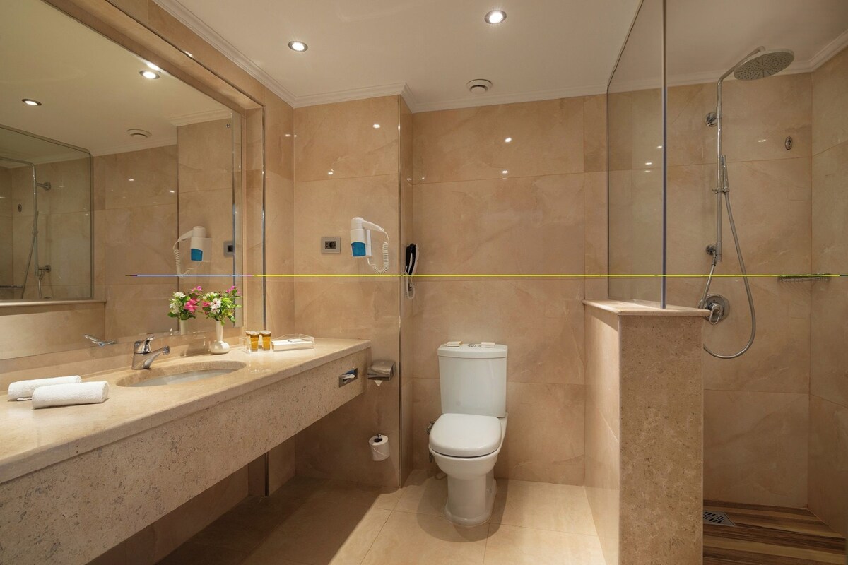 Un baño moderno con cabina de ducha de vidrio, inodoro y tocador con lavabo y espejo.