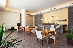 A hotel lobby with a reception desk, seating area with tables and chairs, and a decorative wall with shelves. - Cleopatra Luxury Resort Makadi Bay - Adults Only (Safaga)