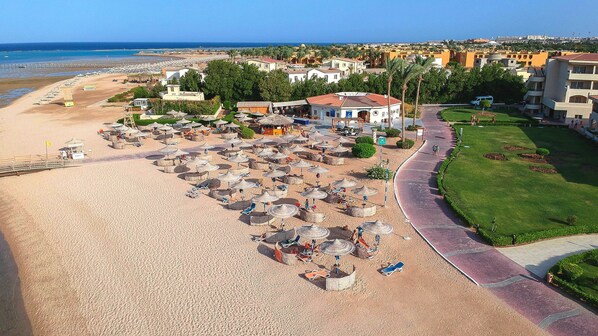 Relax on the beach with thatched umbrellas and sun loungers, surrounded by lush greenery and picturesque sea views.