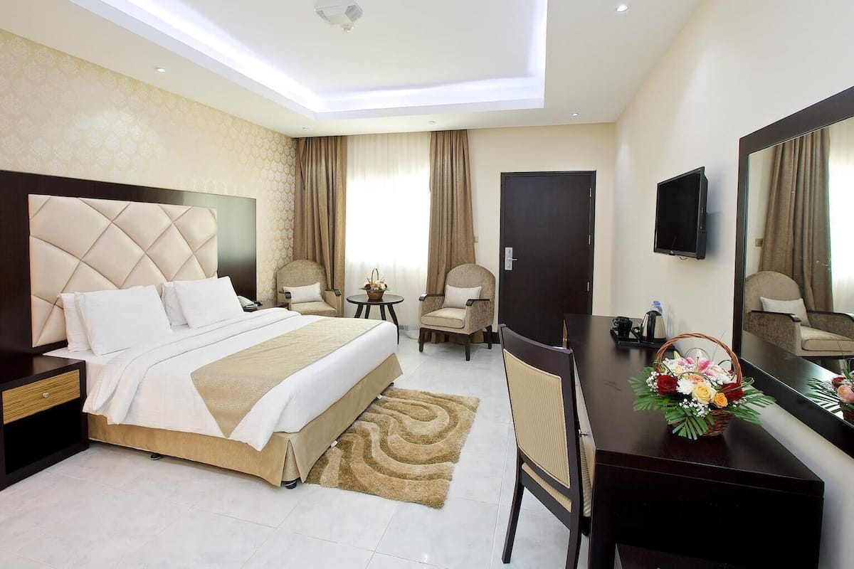 A hotel room with a bed, a desk, a chair, a television, and a mirror.