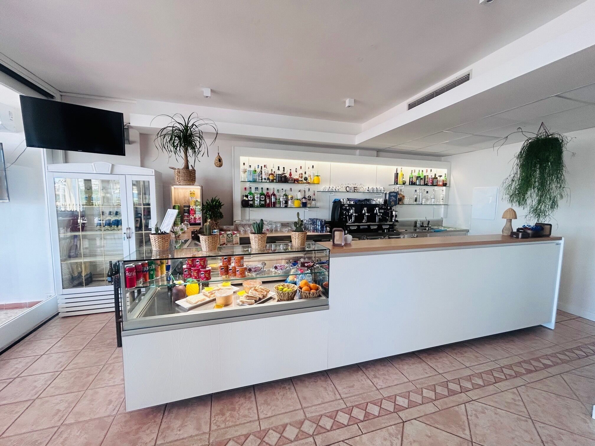 A modern bar area with a counter, display cases, and a coffee machine.