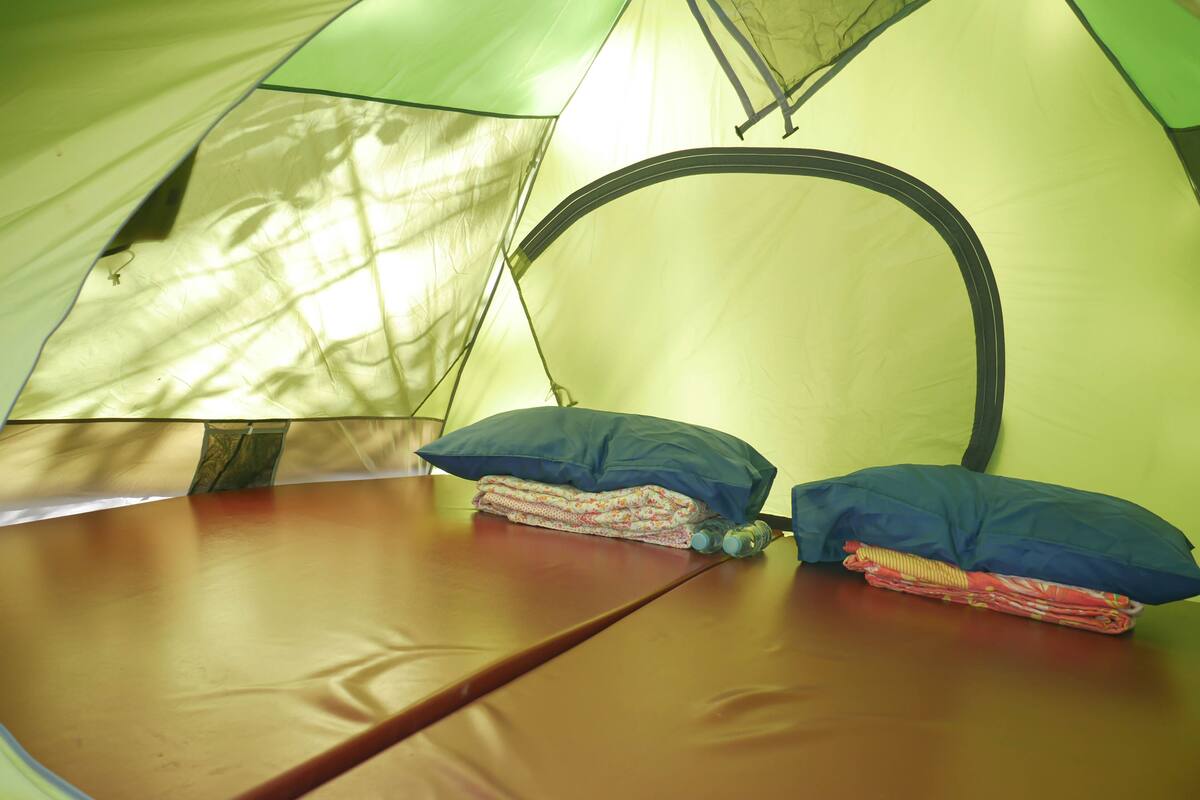 Tienda de campaña con zona de dormir, incluyendo un colchón y almohadas.
