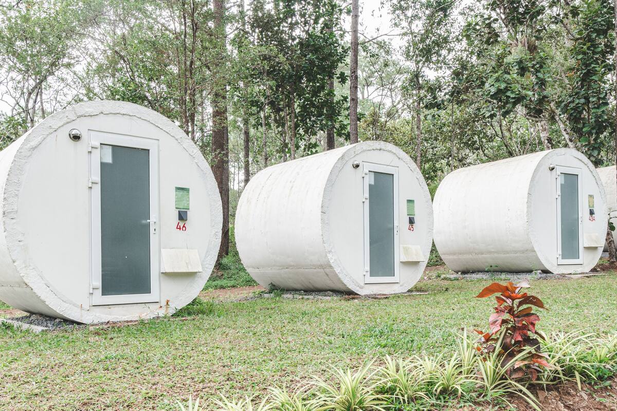 Tres estructuras cilíndricas con puertas, numeradas 46, 45 y 434, ubicadas en un área verde con árboles de fondo.