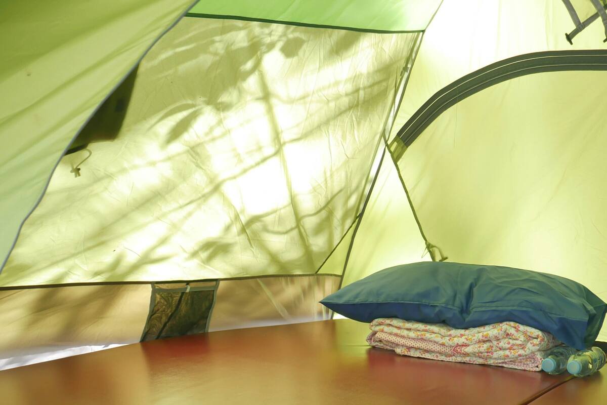 Una carpa con zona de descanso, almohada y mantas dobladas.