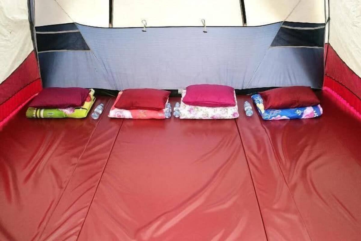 Una carpa con piso rojo y almohadillas.
