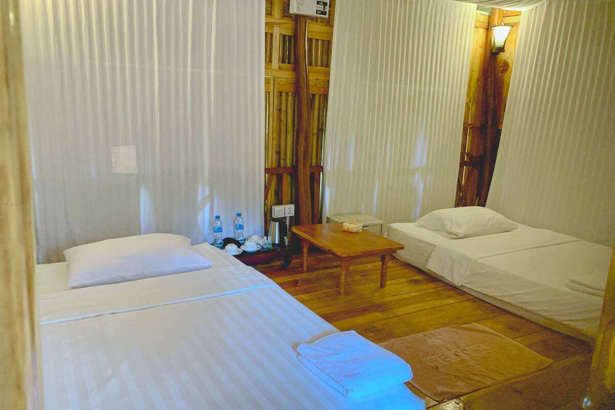 Una habitación de hotel con cama, una mesita, un sofá y suelo de madera.