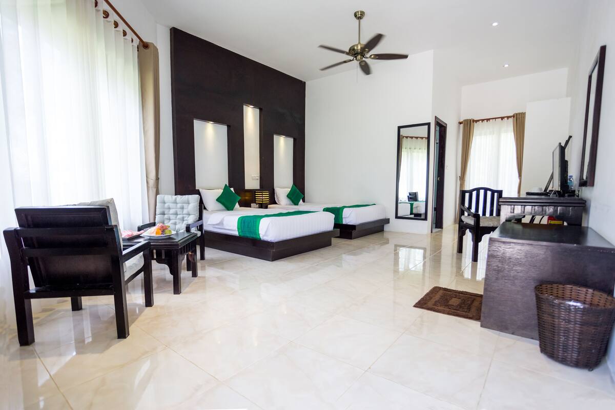 Una habitación de hotel con cama, escritorio, silla, ventilador de techo y un espejo grande.