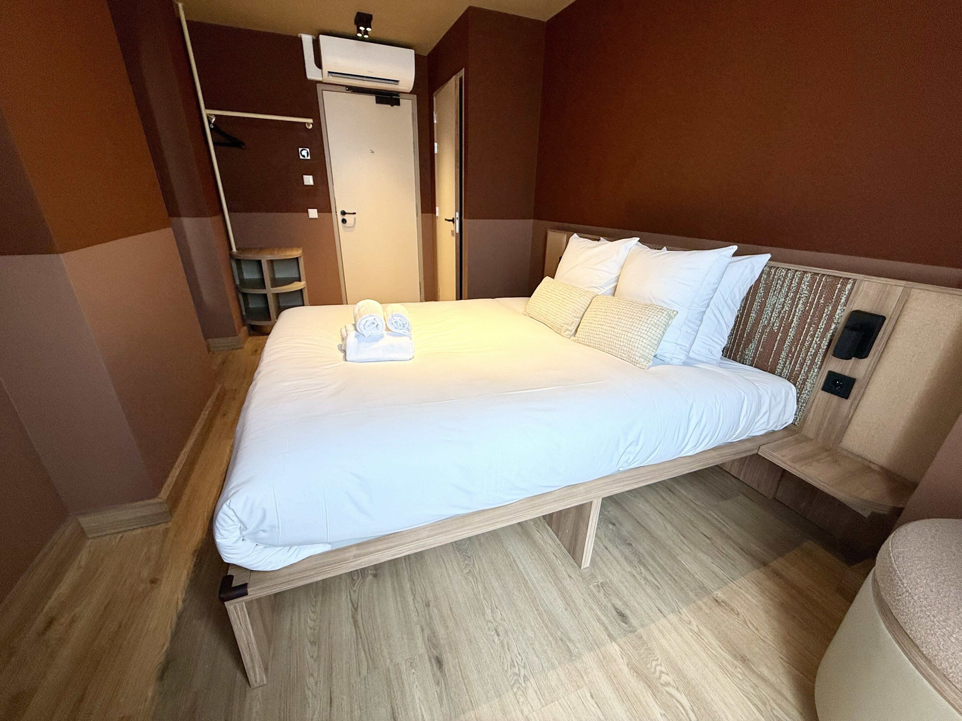 A single bed with white linens, a wooden headboard, and a bedside table with a lamp.