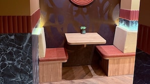 A room with a wooden bench, a small table, and a decorative wall with a circular pattern. - De Pijp Boutique Hotel (Amsterdam)