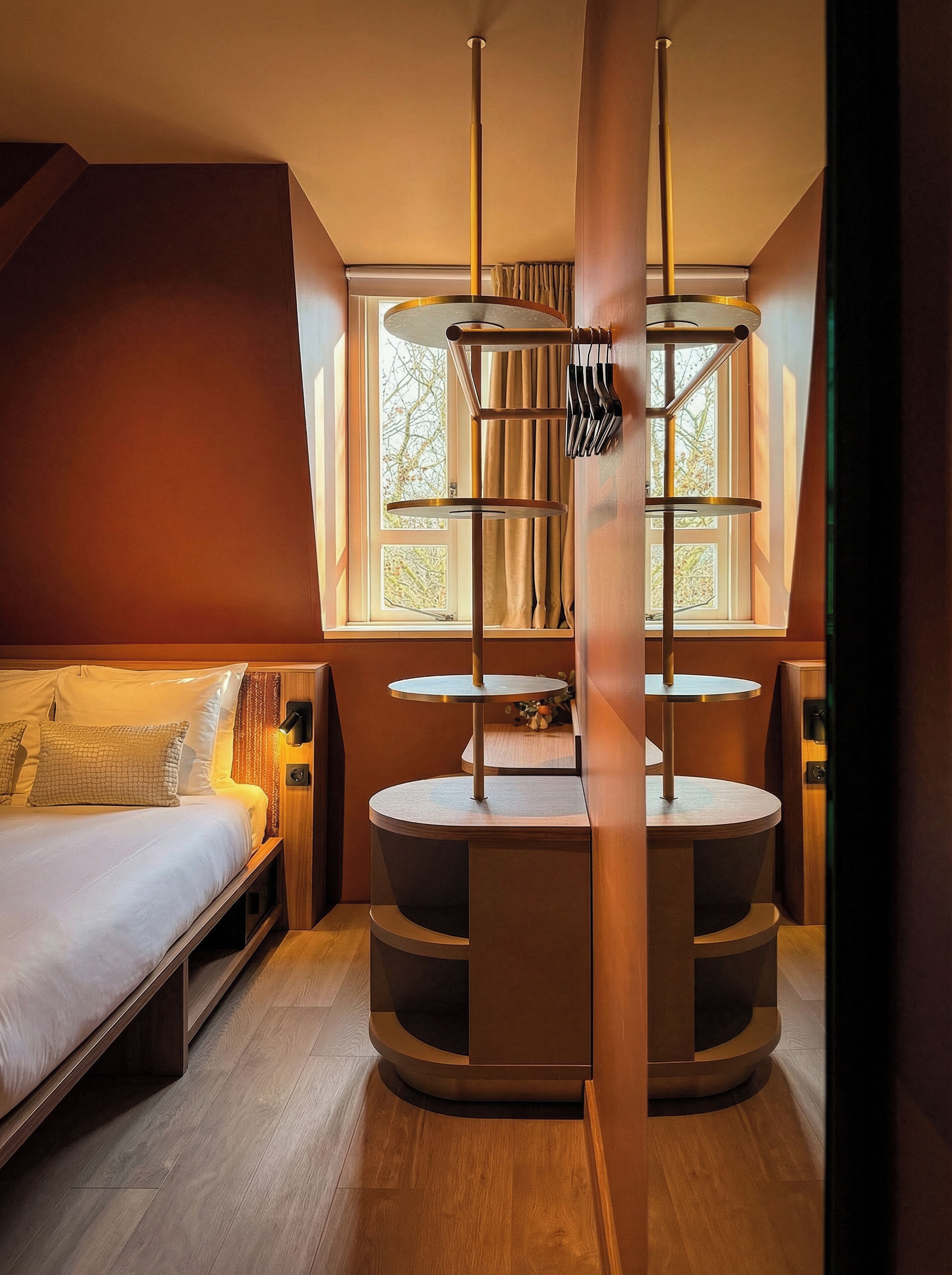 A modern bedroom with a bed, a circular wooden table, and a window with curtains.