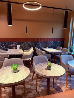 Un restaurante con mesas redondas, sillas y lámparas colgantes.
