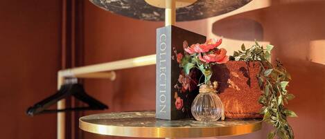A round table with a marble top, a glass vase with flowers, and a hanging plant.