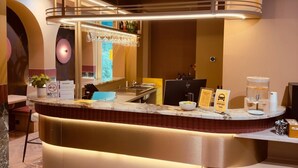 A modern bar area with a curved counter, a glass display case, and a seating area with a bench. - De Pijp Boutique Hotel (Amsterdam)