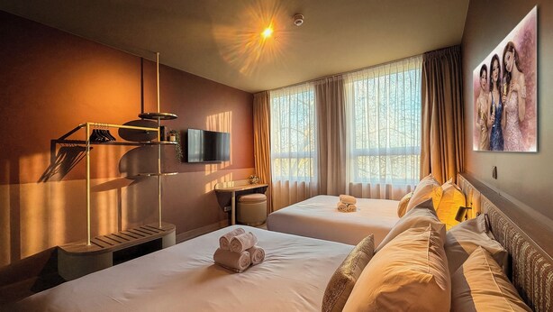 A hotel room with two beds, a TV, a desk, and a painting on the wall. - De Pijp Boutique Hotel (Amsterdam)