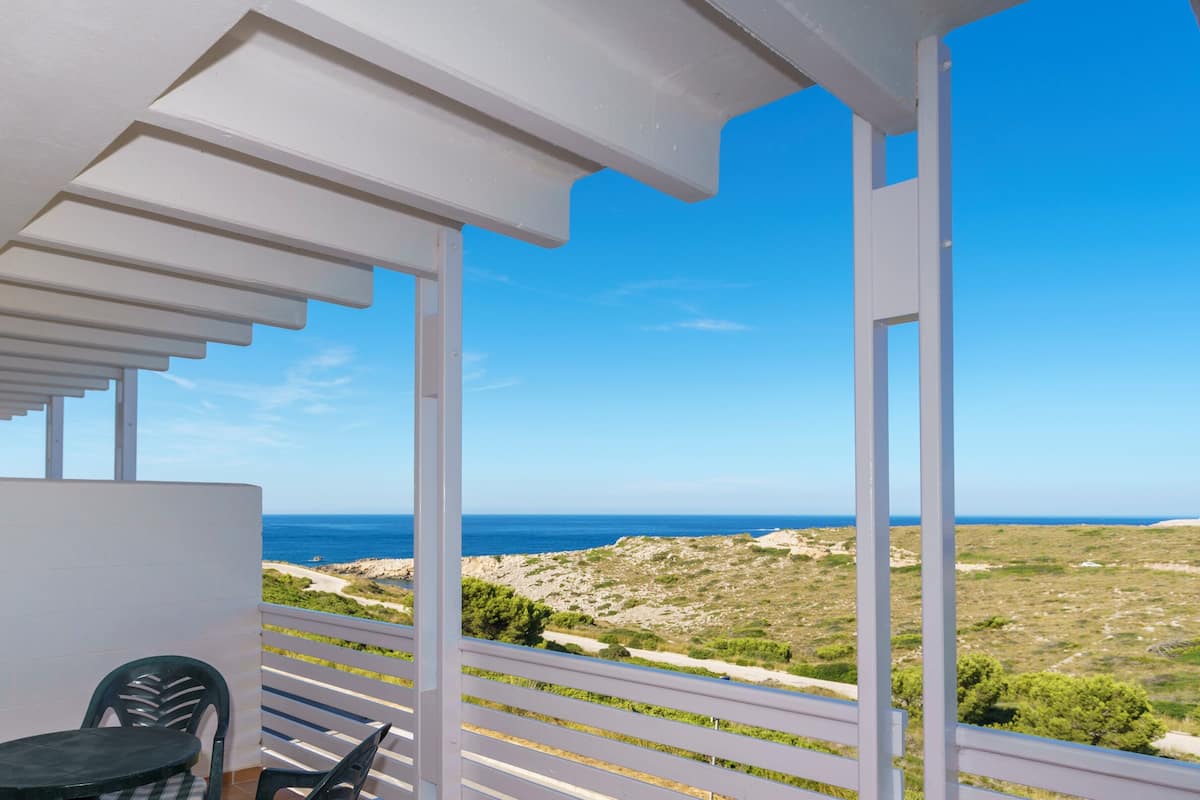 A balcony with a view of the sea and a rocky landscape.
