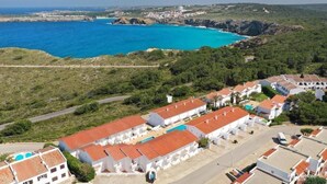 Un pueblo costero con edificios blancos, una piscina y vistas al mar.