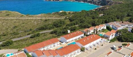 Un village côtier aux bâtiments blancs, doté d’une piscine et offrant une vue sur la mer.