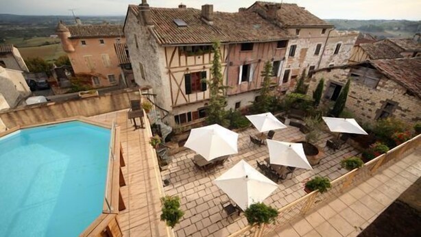 Pátio com piscina, área de estar externa e edifícios de pedra.