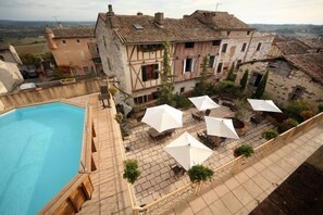 Ein Innenhof mit Schwimmbecken, Sitzgelegenheiten im Freien und Steingebäuden.