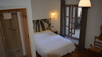Et hotelværelse med seng, brusebad, stol og et vindue med gardiner.