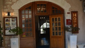 Entrada de hotel com um arco de madeira, uma placa indicando o quarto número 2 e um letreiro com a palavra 'HOTEL'.