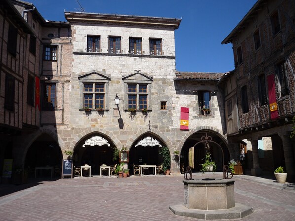 Ein historisches Gebäude mit Rundbogenportalen, Steinmauern und einem zentralen Innenhof mit Sitzgelegenheiten.