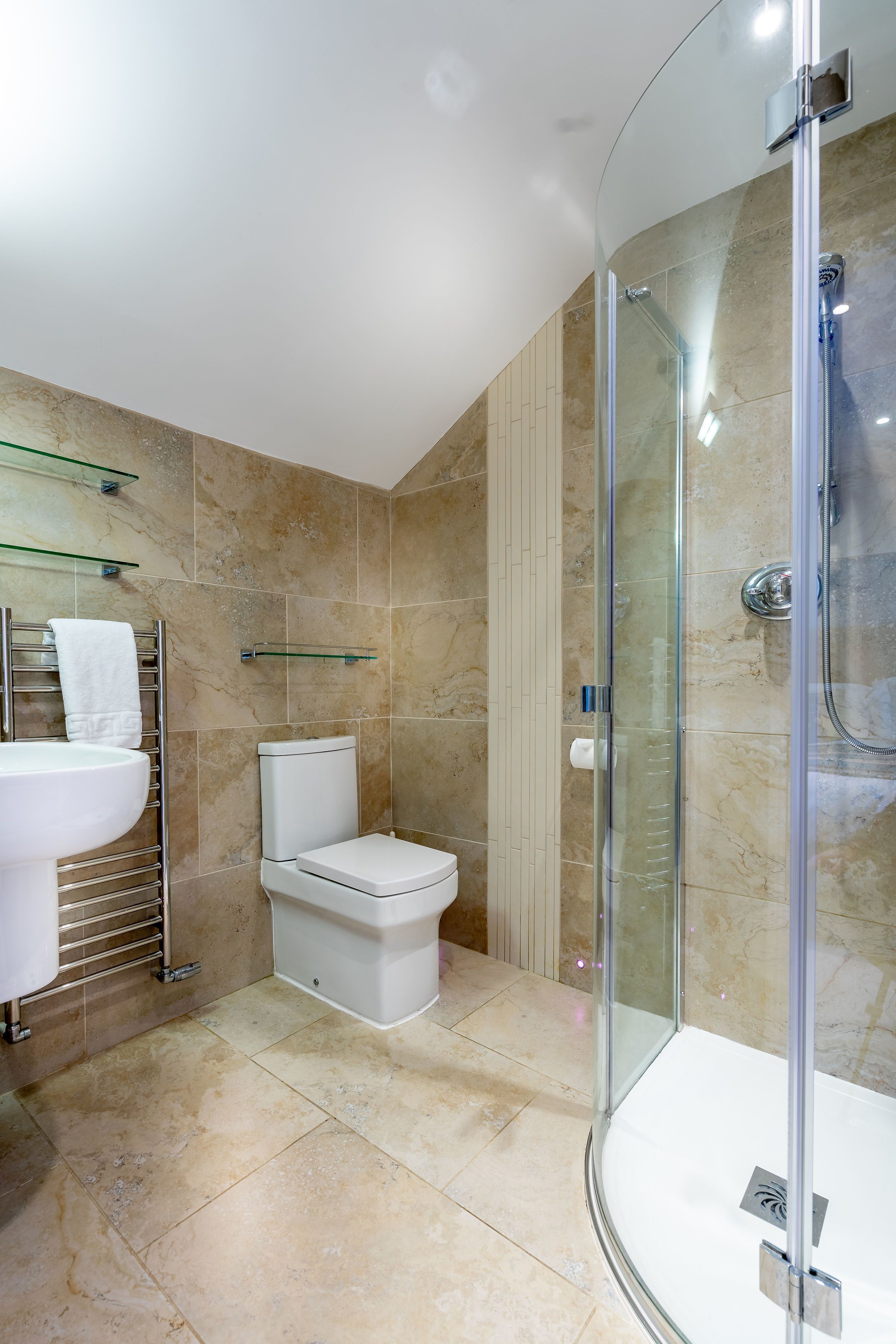 Een moderne badkamer met een douchecabine van glas, een wit wastafelmeubel en een toilet.