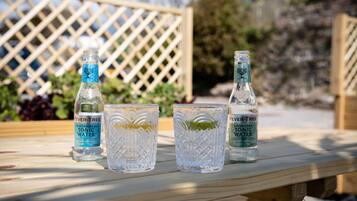 A wooden table with three bottles of tonic water and two glasses.