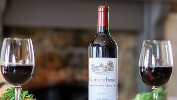 A bottle of Chateau de Fonbel wine, two glasses of red wine, and a plate of food on a table.