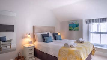 A bedroom with a bed, bedside table, lamp, and a painting on the wall.