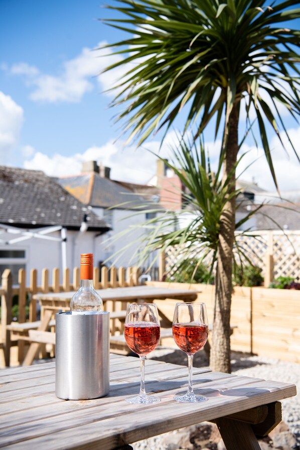 A wooden table with a wine bottle and two glasses of red wine. - Marazion Hotel (Marazion)