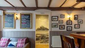 Een restaurantinterieur met een wijnkaart, een bordje 'Toiletten' en ingekaderde foto's aan de muur.