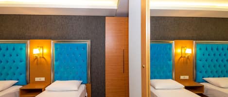 A hotel room with two beds, a wooden wardrobe, and a mirror.