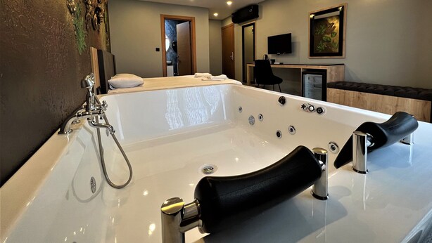 A modern bathroom with a large bathtub, a shower area, and a vanity with a mirror. - Grand Palace Hotel (Istanbul)
