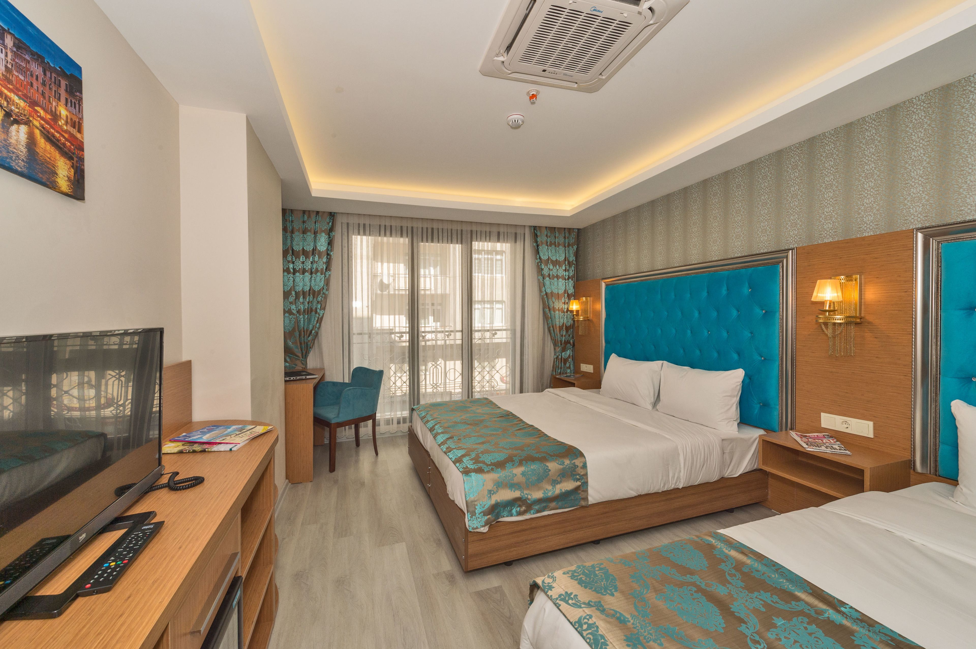 A hotel room with a bed, a desk with a TV, and a chair.